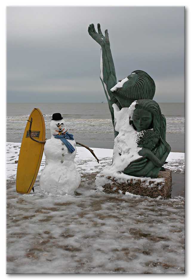 Surfing snowman on the Seawall, next to the hurricane  memorial statue in Galveston.